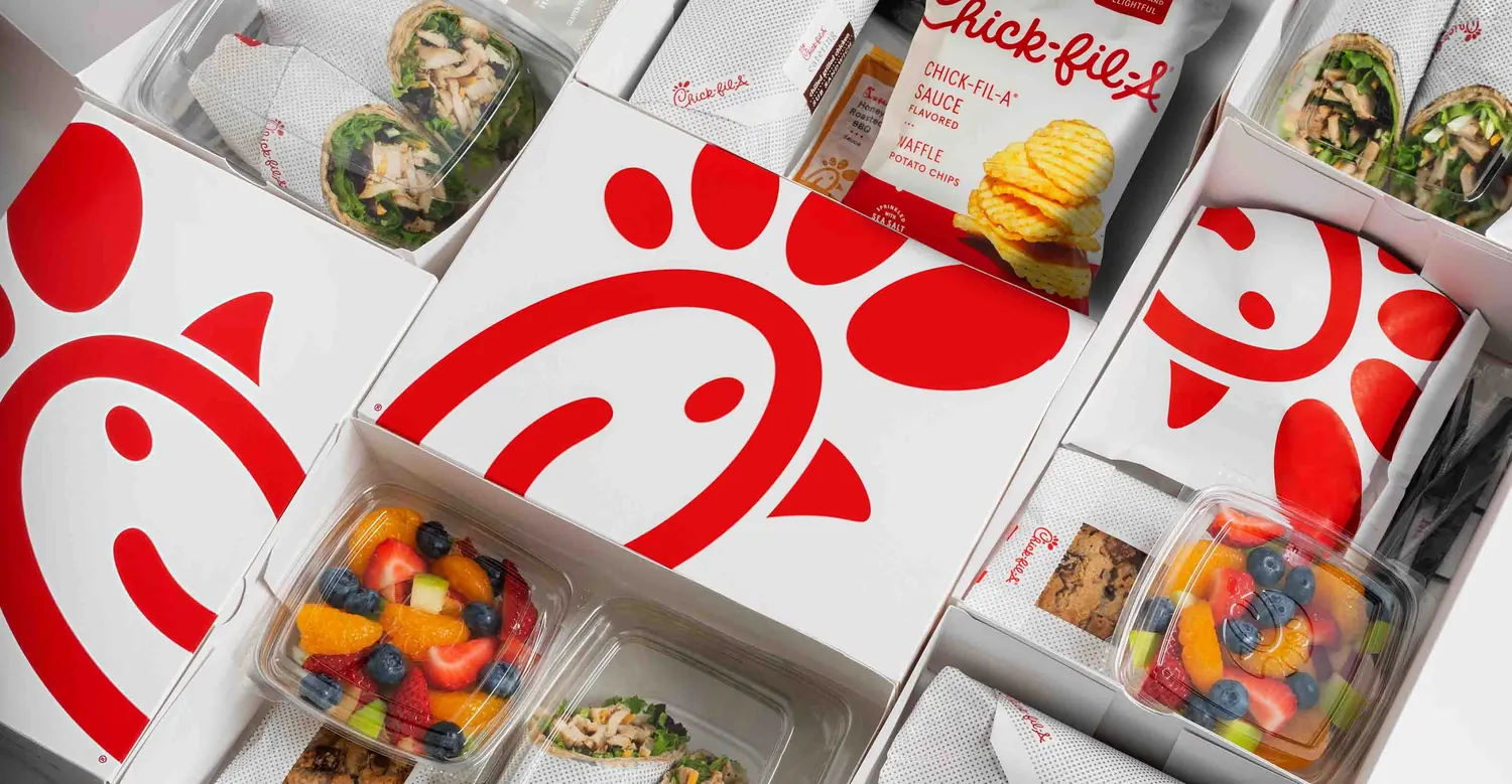 Chick-fil-A packaged catering meals with wraps, fruit, chips, and cookies